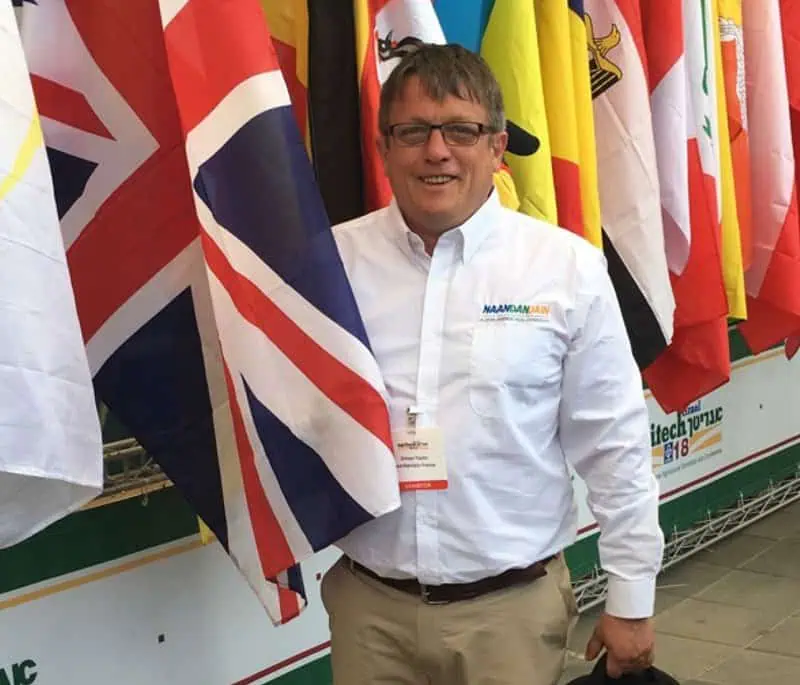 Man in white shirt smiling before international flags